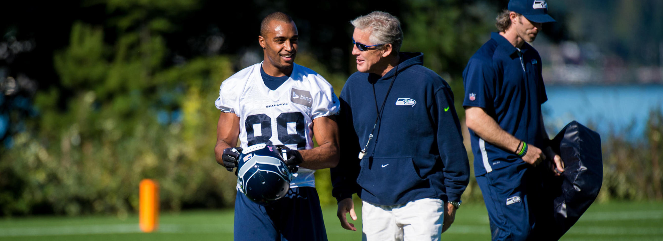 Seahawks coach Pete Carroll talk to a player on the field during practice